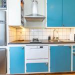 Küche mit blauen Schränken, Edelstahlgeräten und weißer Fliesenwand.
