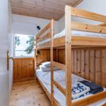 Zimmer mit Holzbett, Fenster und Blick auf Wasser