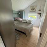 Bedroom with bed, window, and wooden floor. Walls with vertical panels.