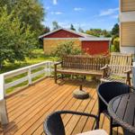 Deck with wooden flooring, garden furniture, and view of an apple tree and a red shed.