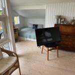 Bedroom with bed, TV, and wooden floor. View of terrace through window.