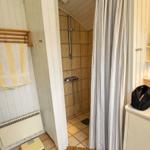 Shower cabin with curtain, shower head, and tiled floor.