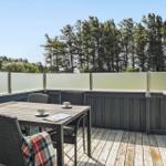 Terrasse mit Tisch und Stühlen, Blick auf Bäume und Himmel.