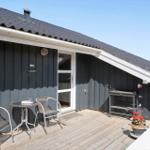 Terrasse mit Tisch, zwei Stühlen und Pflanzen vor einem Haus mit dunkler Fassade.