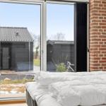 Schlafzimmer mit weißem Bett und großem Fenster zur Außenterrasse.