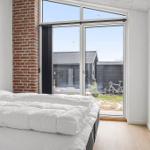 Schlafzimmer mit weißem Bett und großem Fenster zur Außenterrasse.