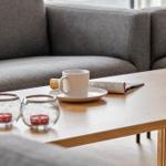 Ein grauer Sofa mit Tisch, Tasse, Zeitschrift und Kerzenhaltern.