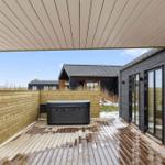 Terrasse mit Whirlpool und Holzverkleidung. Sicht auf moderne Häuser im Hintergrund.