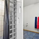 Bathroom with shower, toilet, and sink. Glass blocks separate shower area.