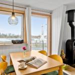 Dining room with wooden table, chairs, and wood stove. View of water and terrace.