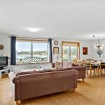 Living and dining area with sofa, TV, and view of water.