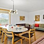Dining room with round table, chairs, and sofa. Walls with pictures and window.