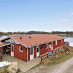 Red building by the lake with grill and entrance area.