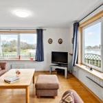 Living room with sofa, coffee table, and TV. Large windows with water view.