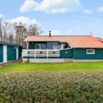 Ein Haus mit Terrasse, grünem Garten und rotem Dach unter blauem Himmel.
