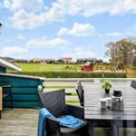 Terrasse mit Tisch, Stühlen und Blick auf grünes Gelände und Spielplatz.