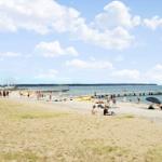 Strand mit Steg, Sonnenbadenden und Rettungsschwimmerstation