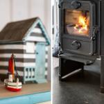 Holzofen mit brennendem Feuer und maritime Dekoration wie Segelboot und Leuchtturm.