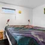 Schlafzimmer mit Bett, Nachttisch, Kleiderschrank und Wandbild.