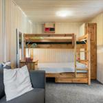 Zimmer mit Holzbett, Sofa und Tür zum Flur.
