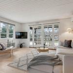 Wohnzimmer mit Sofa, Sessel, TV und Glastüren zum Garten.
