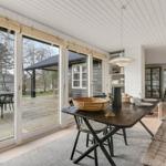 Essbereich mit Tisch, Stühlen und Sitzbank. Große Fenster zeigen Terrasse und Garten.