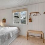 Schlafzimmer mit Bett, Fenster und Holzmöbeln.