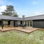 Moderne Holzhütte mit Terrasse und Garten. Grosse Fenster und Sitzgelegenheiten.