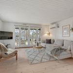 Wohnzimmer mit Sofa, Teppich und Fernseher an der Wand.