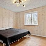 Schlafzimmer mit Holzwand, Bett und Fenster mit Blick auf Bäume.