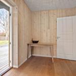 Eingangsbereich mit Holzwand, Tisch und Tür. Durchgang zur Terrasse.