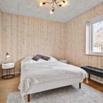 Schlafzimmer mit Holzwand, Bett, Fenster und Bank.