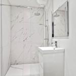 Badezimmer mit Dusche, Waschbecken und Spiegel.