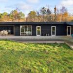 Moderne schwarze Hütte mit Terrasse und Garten. Sichtbar: Tisch, Stühle, Fenster, Türen.