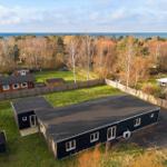 Moderne schwarze Ferienhaus mit Garten und Blick auf Meer.