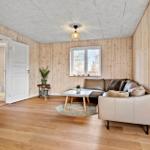 Wohnzimmer mit Holzwand, Sofa, Tisch und Fenster. Tür führt in Bad.