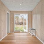 Hallenraum mit Holzwänden, Boden und Tür zur Außenterrasse.