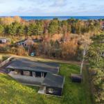 Modernes Haus mit Terrasse, umgeben von Wald und Blick auf Meer.
