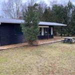 Wooden house with porch, picnic table, and tree in yard
