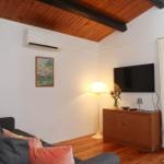 Living room with sofa, TV, and wooden floor. Door leads to terrace.
