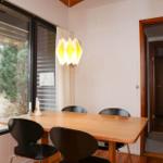 Dining room with wooden table, black chairs, and large window to the garden.