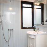 Bathroom with shower, sink, and toilet. Window with frosted glass.
