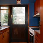 Kitchen with wooden cabinets, refrigerator, and door to outside area.