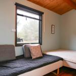 A bedroom with two beds, a window, and a wooden ceiling.
