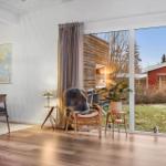 Living space with wooden floor, seating area, and view of garden and outbuilding.