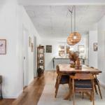 Dining area with wooden table, chairs, and world map. Kitchen in background.