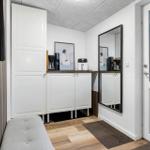 Entryway with mirror cabinet, coffee machine, and wooden floor.