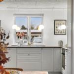 Kitchen with white cabinets, window, and pendant lights. Decorative pictures on the walls.