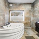Bath with whirlpool, wall cladding, and sink with mirror.