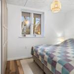 Bedroom with bed, window, and quilt. Wooden floor and lamp.
